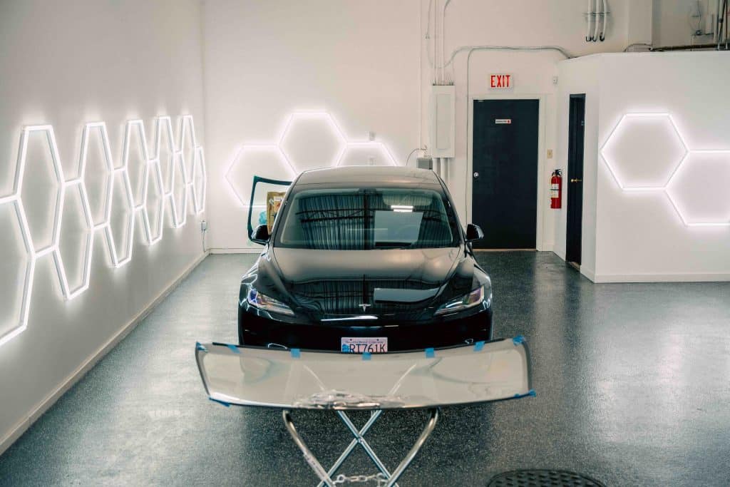 Tesla prepared for windshield replacement with new glass staged on a stand at Crown Auto Glass Burnaby.