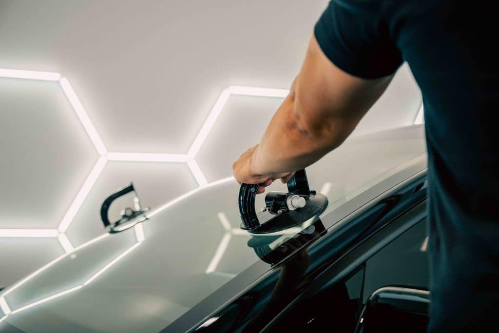 Auto glass technician positioning a suction lifter on a vehicle windshield in Burnaby.
