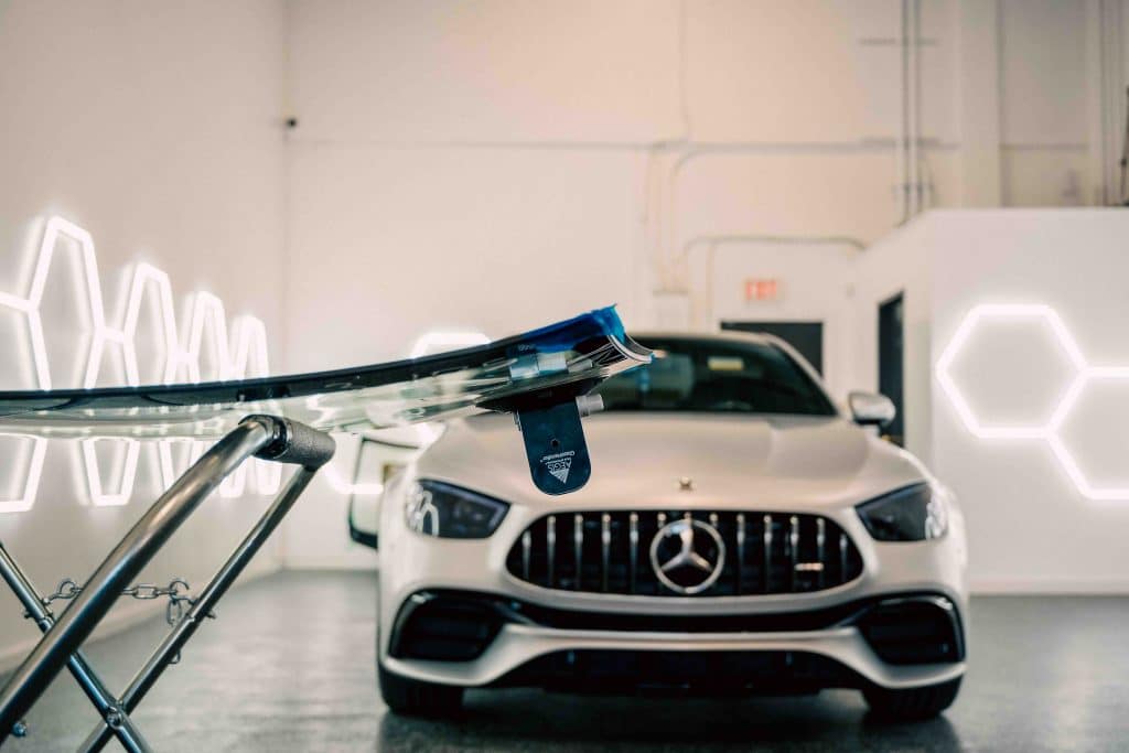 Technician preparing a replacement windshield on a stand.